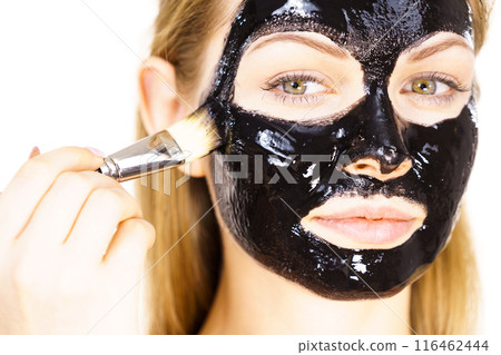 Woman applying black mud mask to face Woman applying black mud mask to face 116462444