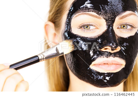 Woman applying black mud mask to face Woman applying black mud mask to face 116462445
