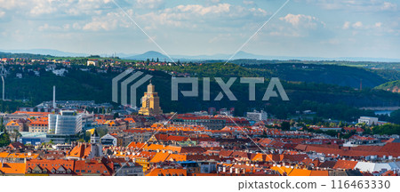 A panoramic view of Prague from a high vantage point, showcasing the iconic Hotel International Tower. Nestled in the distance are the rolling hills and lush greenery that surround the city. 116463330