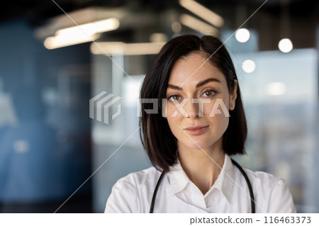 Portrait of confident female doctor standing in modern medical office with stethoscope around neck. Professional healthcare worker with serious expression in contemporary clinical setting 116463373
