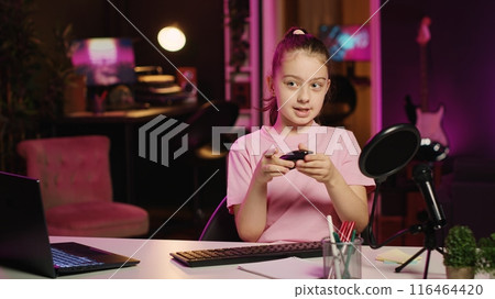 Kid content creator filming keyboard review in home studio, pressing different buttons to show typing capabilities. Little girl showcasing computer peripherals to audience on gen Z online channel 116464420