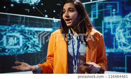 Speaker talking with audience on stage at AI conference bringing together leading experts and researchers to explore latest developments in artificial intelligence and machine learning, camera B 116464461