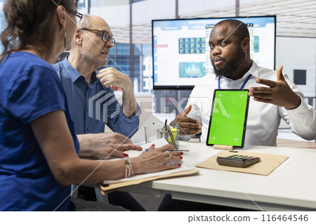 Senior citizens exploring retirement planning options with advisor, discussing next to chroma key display on tablet. Ensuring life savings protection and growth for the future. 116464546