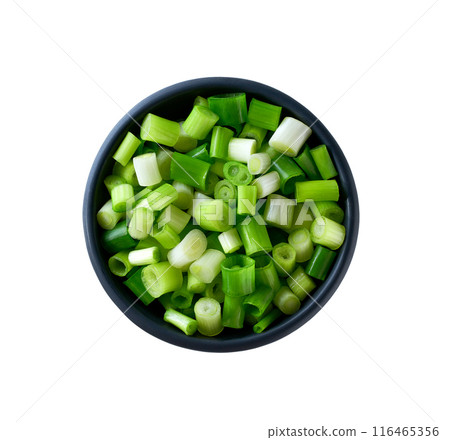 Chopped spring onions in a black ceramic bowl isolated on white background. Top view. 116465356