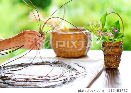 A woman weaving a basket and handmade baskets 116465782