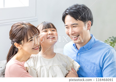 Smiling young family relaxing in the living room Smiling young family relaxing in the living room 116468091
