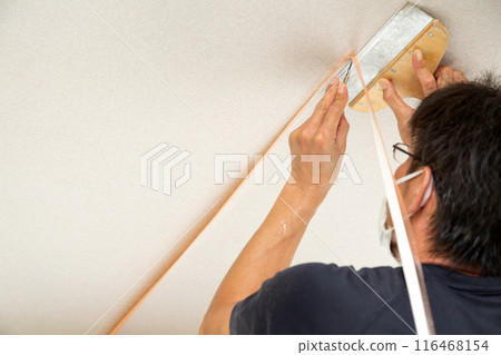 A craftsman laying wallpaper during the renovation of a used house 116468154