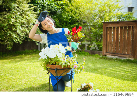 一位微笑的中年婦女正在種樹 116469694