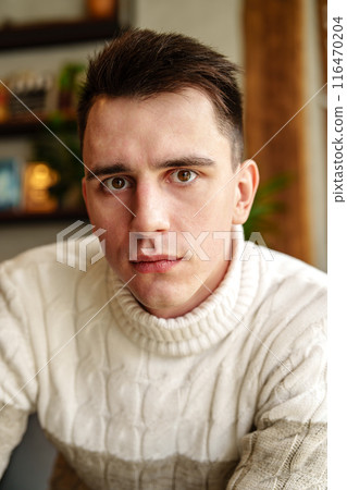Man in White Sweater Looking at Camera 116470204