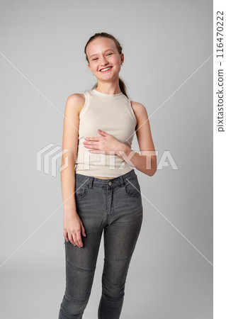 Girl in Beige Tank Top and Grey Jeans on gray background Girl in Beige Tank Top and Grey Jeans on gray background 116470222