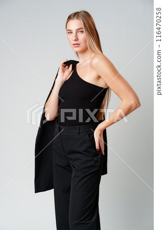 Young Woman Model in Black Top and Pants Posing on gray background 116470258