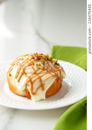 Cinnamon roll bun with icing on plate Cinnamon roll bun with icing on plate 116470488
