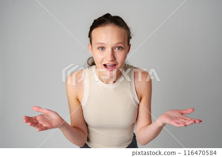 Young Clueless Woman Standing With Outstretched Arms on gray background 116470584