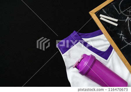 White and Purple Sports Uniform and Water Bottle Next to a Chalkboard on Black Background White and Purple Sports Uniform and Water Bottle Next to a Chalkboard on Black Background 116470673