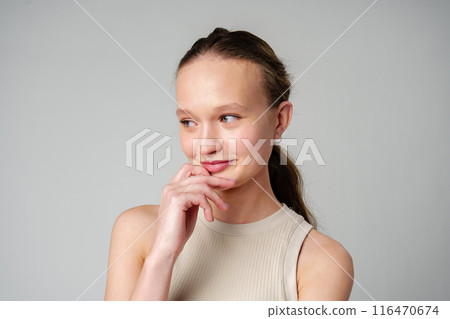 Young Woman Posing deep in thought on gray background Young Woman Posing deep in thought on gray background 116470674