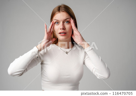 Young Woman Expressing Surprise or Confusion Against a Grey Background Young Woman Expressing Surprise or Confusion Against a Grey Background 116470705