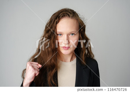 Young Woman in Casual Attire Smiling and Making a Fist Pump Gesture on a Plain Background 116470726