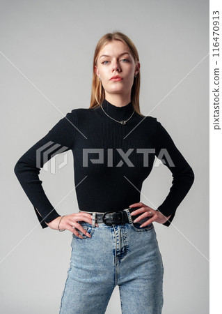 Young Woman Wearing Black Top and Jeans against gray background Young Woman Wearing Black Top and Jeans against gray background 116470913
