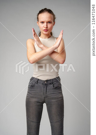 Young Woman Making Stop Sign With Hands on gray background Young Woman Making Stop Sign With Hands on gray background 116471048