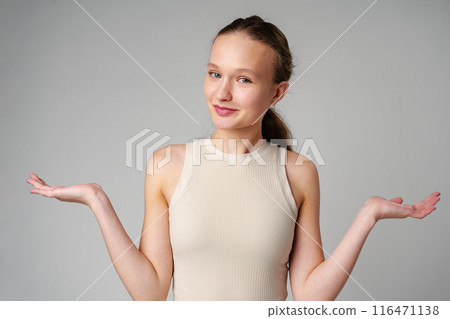 Young Clueless Woman Standing With Outstretched Arms on gray background 116471138