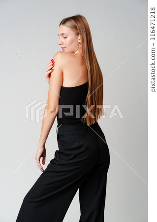 Young Woman Model in Black Top and Pants Posing on gray background Young Woman Model in Black Top and Pants Posing on gray background 116471218