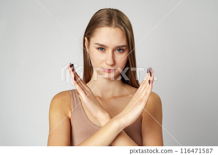 Young serious woman crossed hands show stop symbol on gray background 116471587