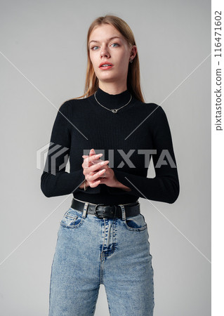Young Woman Wearing Black Top and Jeans against gray background 116471602