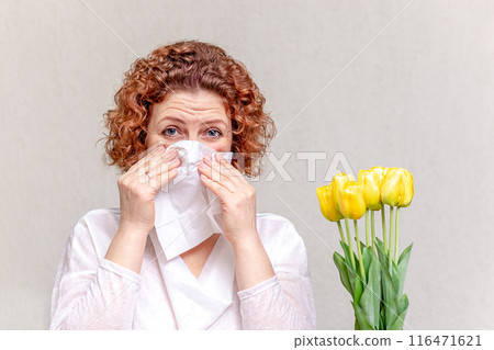 Allergic girl and a bouquet of flowers - yellow tulips on a gray background. Allergic girl and a bouquet of flowers - yellow tulips on a gray background. 116471621
