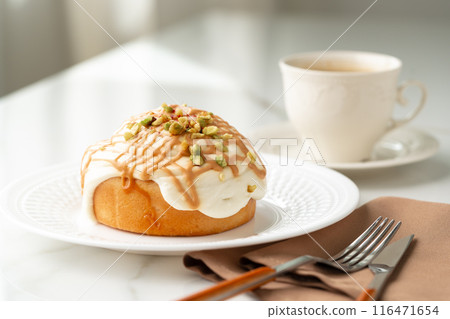 Cinnamon roll bun with icing on plate 116471654