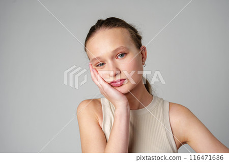 Young Woman Grimacing in Displeasure Against a Neutral Background Young Woman Grimacing in Displeasure Against a Neutral Background 116471686