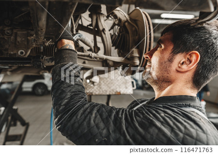 Auto mechanic repairs running gear of a car in car service 116471763