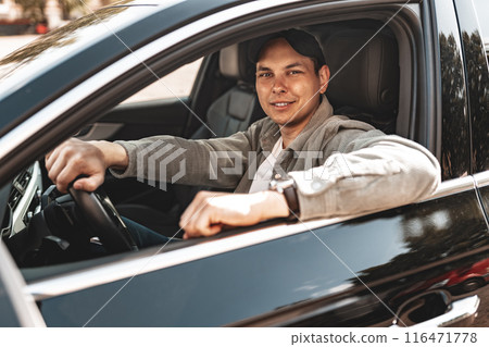 Young smiling man sitting in a car with open window Young smiling man sitting in a car with open window 116471778