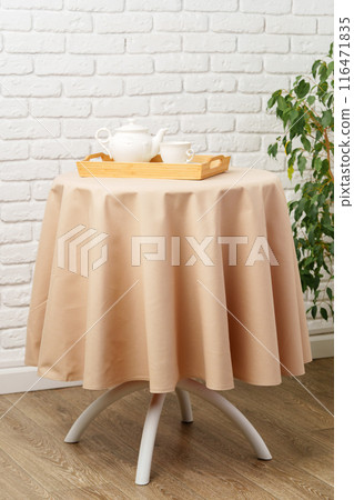 White Teapot and Cup on Wooden Tray on Tan Tablecloth White Teapot and Cup on Wooden Tray on Tan Tablecloth 116471835