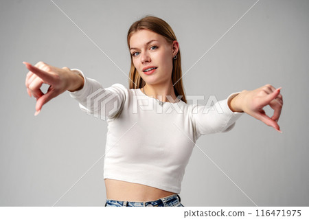Smiling Young Woman With Braces Pointing Towards Camera in Studio 116471975