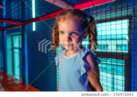 Young Girl With Curly Hair Exploring an Indoor Play Area During Evening Hours 116472041