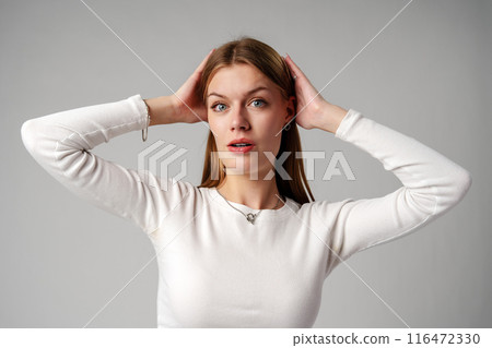 Young Woman Expressing Surprise or Confusion Against a Grey Background Young Woman Expressing Surprise or Confusion Against a Grey Background 116472330