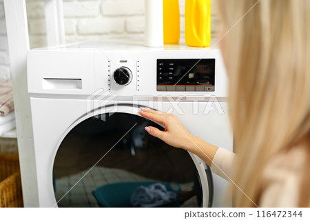 Woman Setting Washing Machine Cycle in Laundry Room Woman Setting Washing Machine Cycle in Laundry Room 116472344