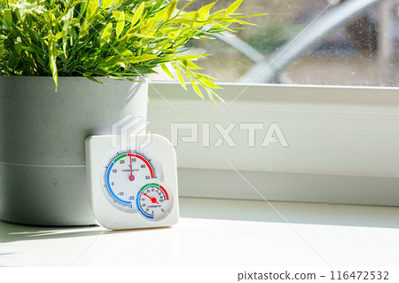 White Hygrometer On Windowsill With Potted Plant 116472532
