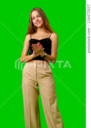 Young Woman Standing With Folded Hands against green background Young Woman Standing With Folded Hands against green background 116472627