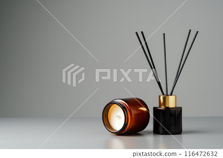 Amber Glass Candle and Reed Diffuser on Grey Surface Amber Glass Candle and Reed Diffuser on Grey Surface 116472632