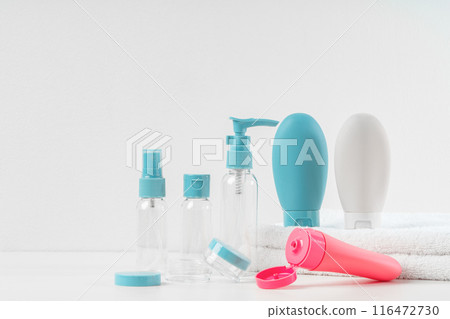 Blue, Pink, and White Travel-Sized Bottles on White Towels 116472730