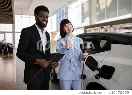 Dealer selling electric SUV to business woman at car dealership Dealer selling electric SUV to business woman at car dealership 116472979