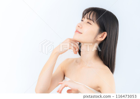 A middle-aged woman doing skin care against a white background 116473053