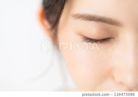 A middle-aged woman doing skin care against a white background 116473096