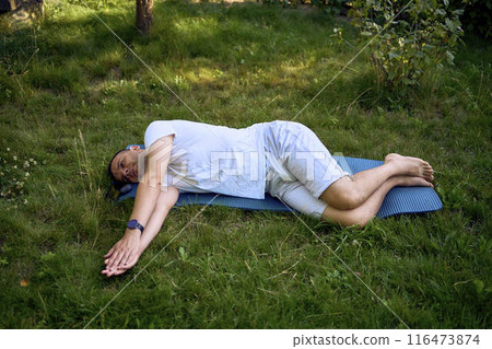 a man performs somatic exercises in the garden in the morning 116473874