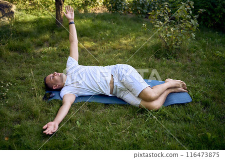 a man performs somatic exercises in the garden in the morning a man performs somatic exercises in the garden in the morning 116473875