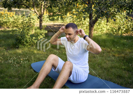 a man performs somatic exercises in the garden in the morning 116473887
