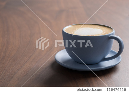 Fresh cappuccino in a blue cup on walnut table with copy space Fresh cappuccino in a blue cup on walnut table with copy space 116476336