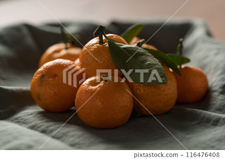 Small organic tangerines with leaves on linen napkin Small organic tangerines with leaves on linen napkin 116476408