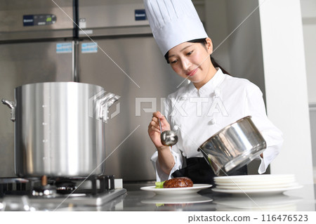 Young Asian female chef serving food on a plate Young Asian female chef serving food on a plate 116476523